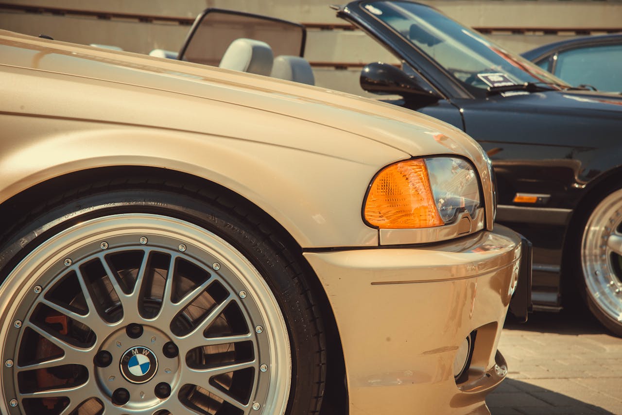 about-01 Detail view of vintage BMW convertibles in an outdoor setting, showcasing sleek design and glossy paint.